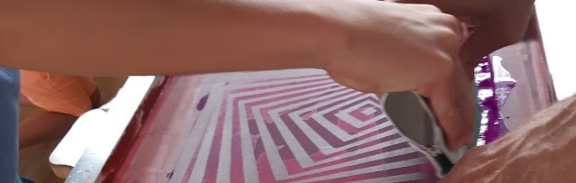 Adult and child holding a squeegee and drag ing ink across a silkscreen fram