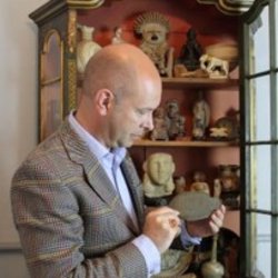 man looking at antique object from cabinet of curiosities