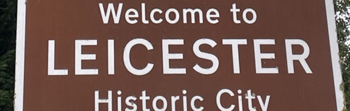 A sign saying 'Welcome to Leicester, Historic City'. A image featuring the clock tower and the surrounding buildings is located over the sign.