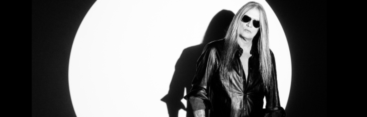 Sebastian bach a man with long hair and tattoos reaching up the staircase with a serious rock face