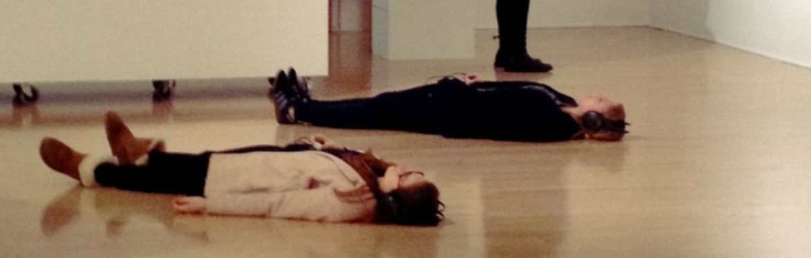 Visitors lying on the floor of Bonnington Gallery with headphones on.