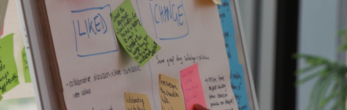 Photo focussing on arms and hands of a group of people working with paper, scissors and graphics.