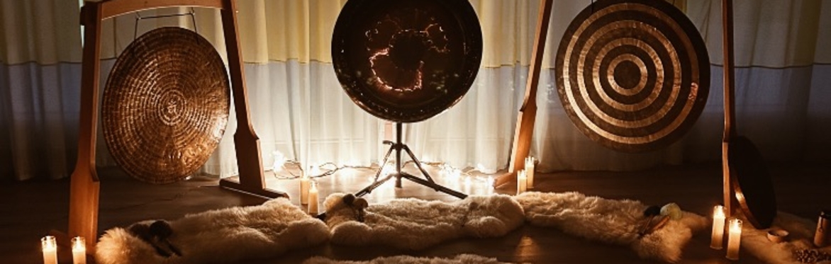 3 large gongs in wooden stands among candles