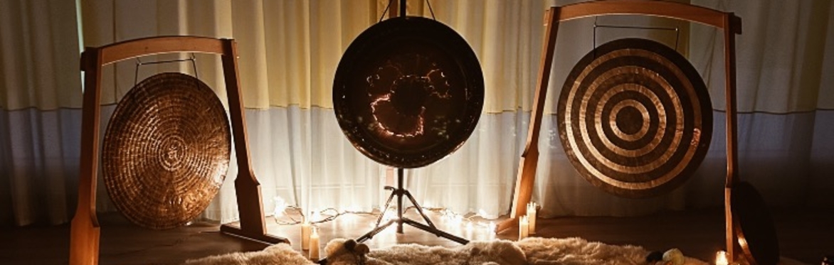 3 large gongs in wooden stands among candles