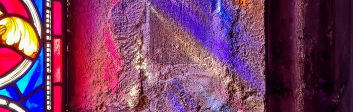 Stained glass reflecting onto stone window frame