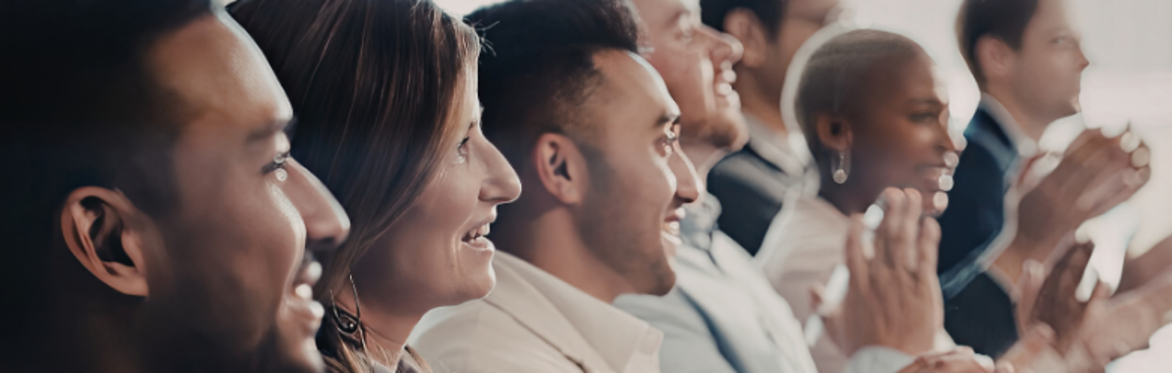 A group of people sitting in a row, smiling and applauding.