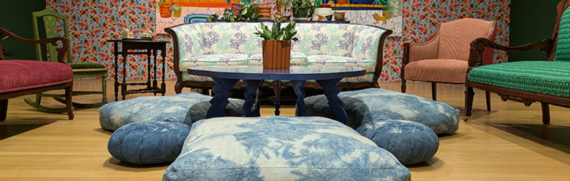 A living room with wallpaper, sofa and floor cushions