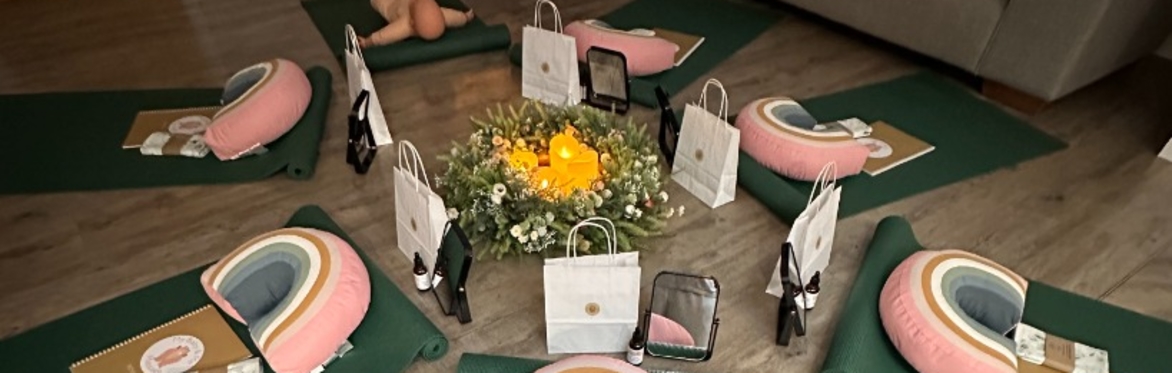 A set up of a rainbow pillow with gift bags and a centerpiece of greenery and candles