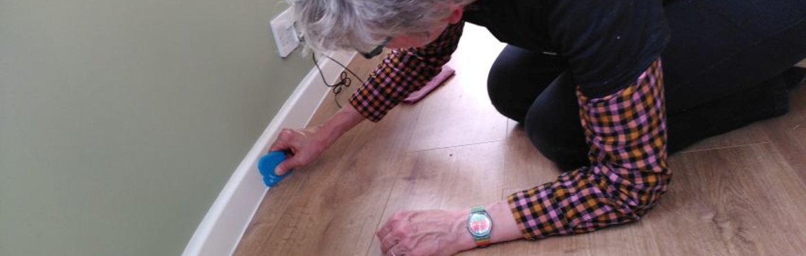 Camilla of Wrapt Homes sealing a gap between a floor and skirting board