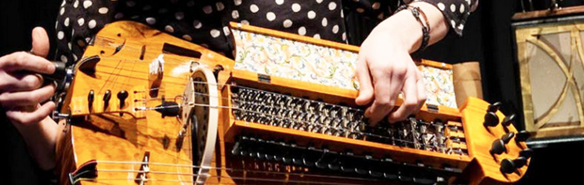 Hand holding an electronic bow over the strings of a harpsichord