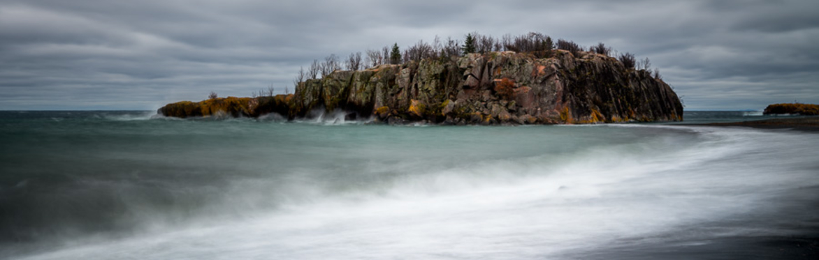 A small island under stormy clouds and a wavy shoreline