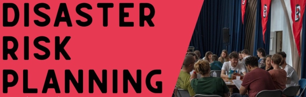 Graphic - text reads ‘Disaster risk planning’ on a red slanted background in the space is a photo from a previous event. Groups of people are sat around tables in a hall, talking.