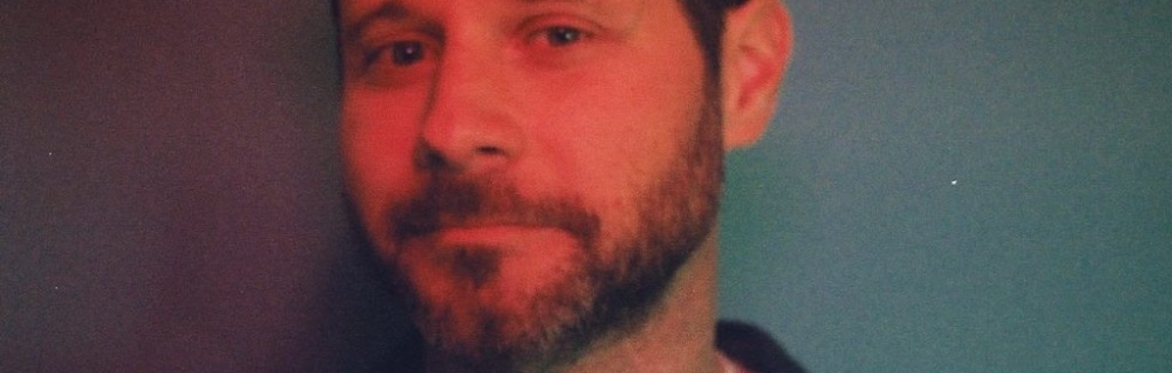 Dan Mangan profile picture in blue and red.