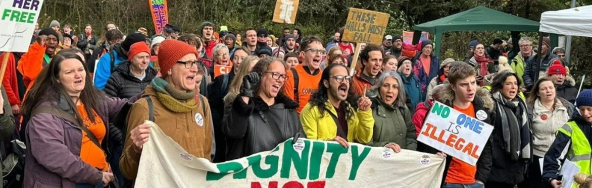 A crowd of protestors, with large banner which reads: DIGNITY NOT DETENTION.