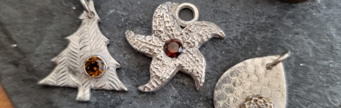 Four Silver Pendants lined up on a wooden background