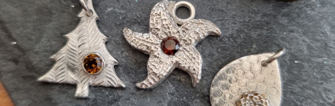 Four Silver Pendants lined up on a wooden background