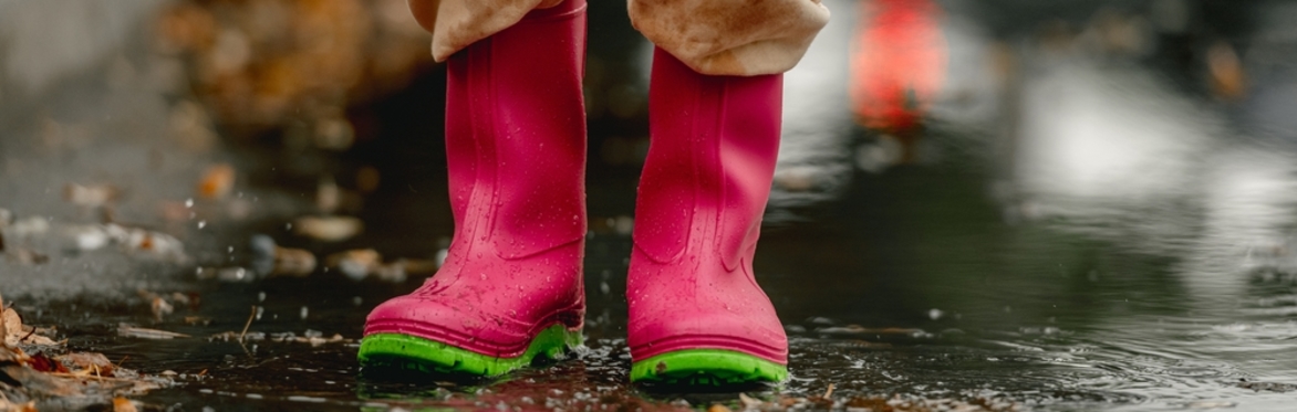 Child with pink wellies standing in a puddle