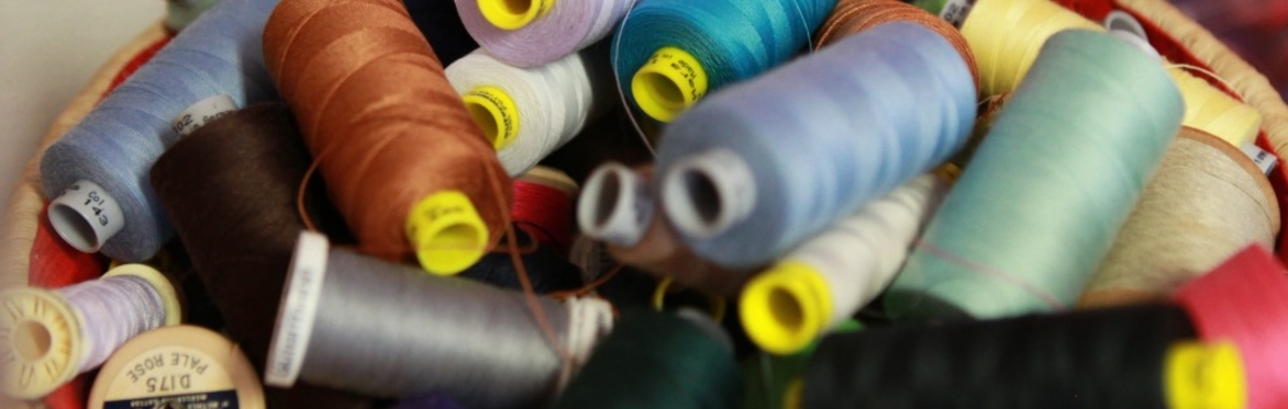 A bowl of sewing thread bobbins in different colours