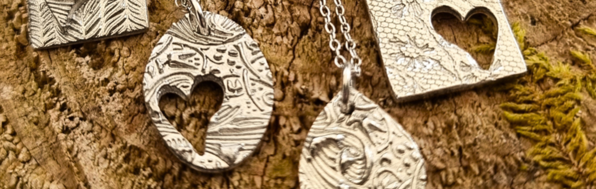 Four Silver Pendants lined up on a wooden background