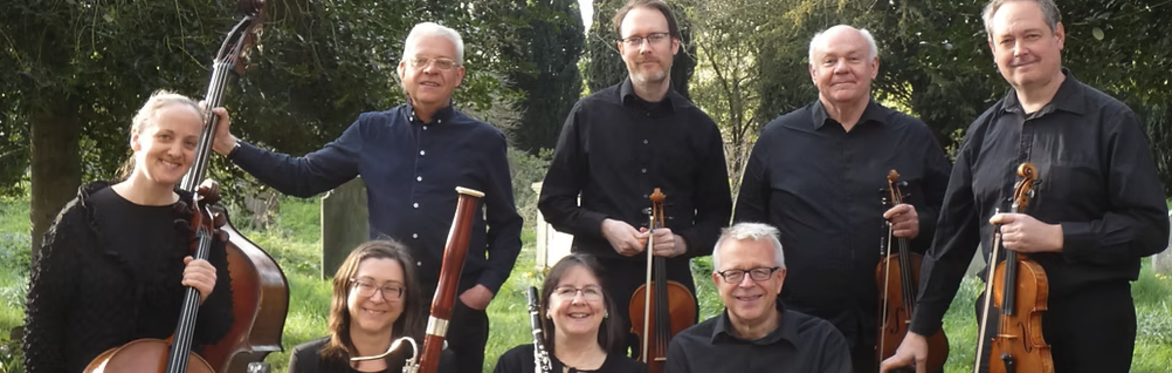 8 Blaze Ensemble musicians, holding their instruments and smiling in a green outdoor space