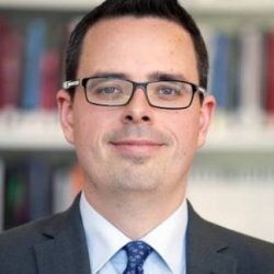 Headshot of Dr Toby Simpson on blurred background