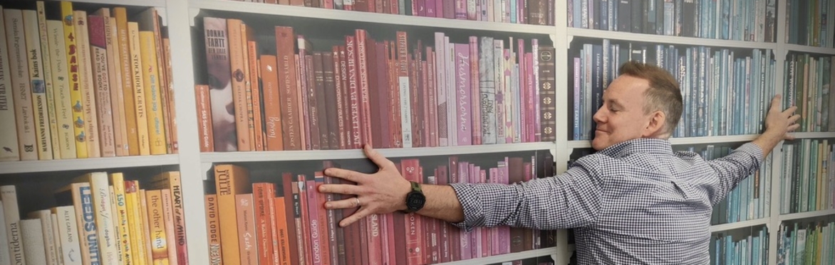 Noel hugging a wall of books