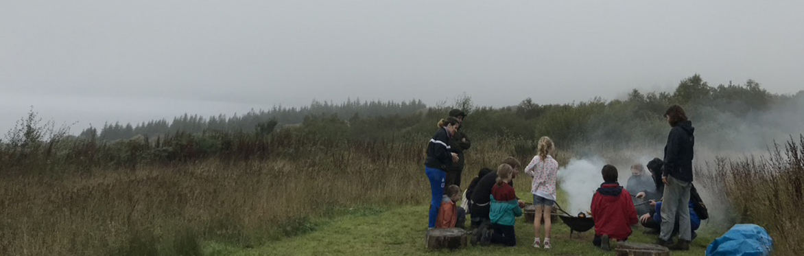 children and adults standing around a Fire Pit at Cove Park
