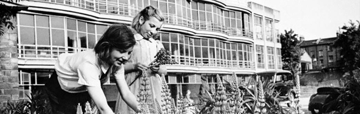 Black and white photo of women gardening in front of Pioneer Building in Peckham