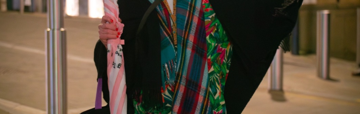 tour guide with pink umbrella and black cape pointing