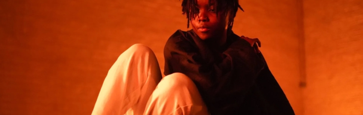 A person the middle of a movement performance, they are on the ground leaning backwards with their knees in up.