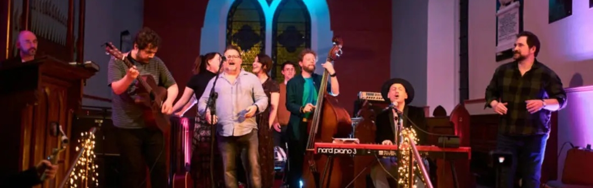 This image is of people singing and playing music onstage in St. Mary's Church Leixlip
