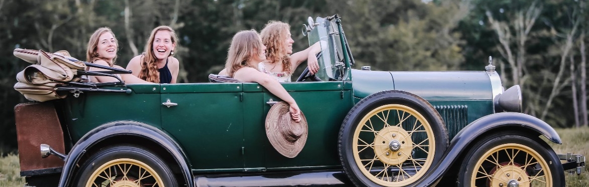 The four Green Sisters sitting in an old convertible car
