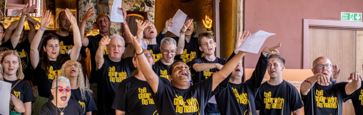 This a picture of CWNN Sheffield at a performance, looking joyful with their arms in the air
