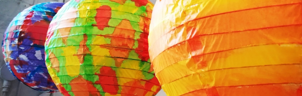 3 colourful painted lanterns are strung up in a room