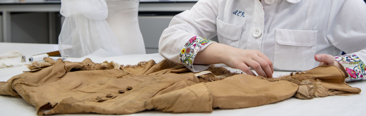 A textile conservator examining a historic bodice.