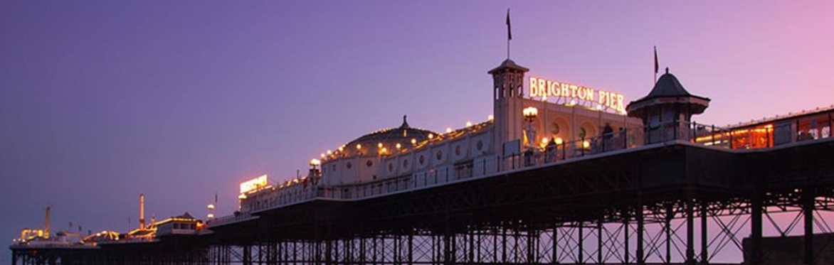 A landscape photo of Brighton pier lit up in the sunset