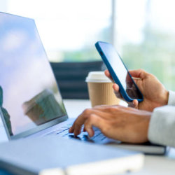 Close up of a businessman working on a laptop and holding and working on a mobile in the office