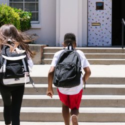 Youth with backpacks running into school