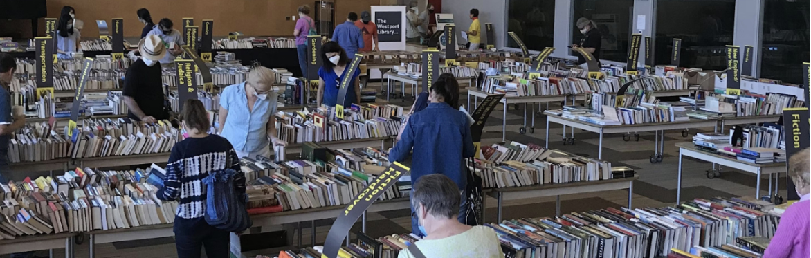 Several people perusing books displayed on tables