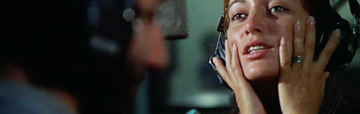 A close up of a person wearing a headset with their hands held to their cheeks.