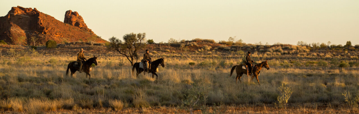 Still image from the film sweet country of three figures on horeback amidst the arid australian outback.