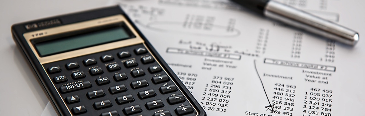 Desk covered with invoices and books with text overlaid "Taxation and Basic Accountancy Workshop with Albert Goodman"