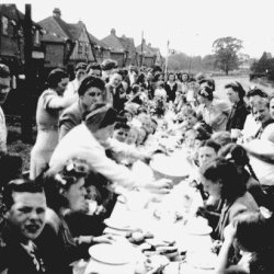 A black and white photograph showing families having a street party for VE Day, Hemel Hempstead