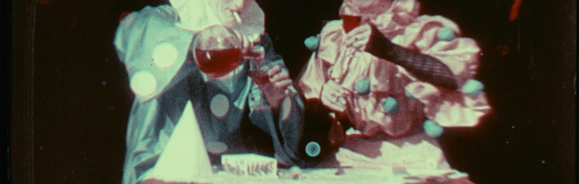 A picture of a man and a woman dressed in green and red clown outfits pouring wine and holding glasses preparing to celebrate.