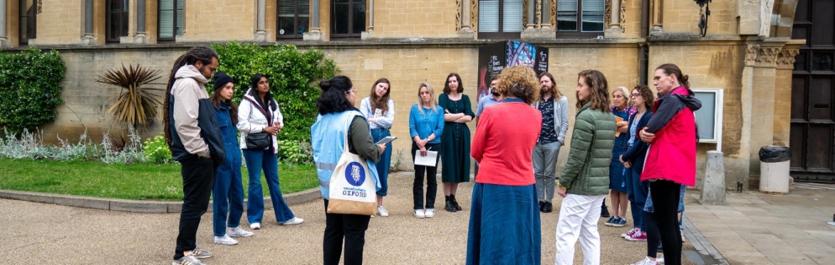 a group of people looking at a guide outside of an old building