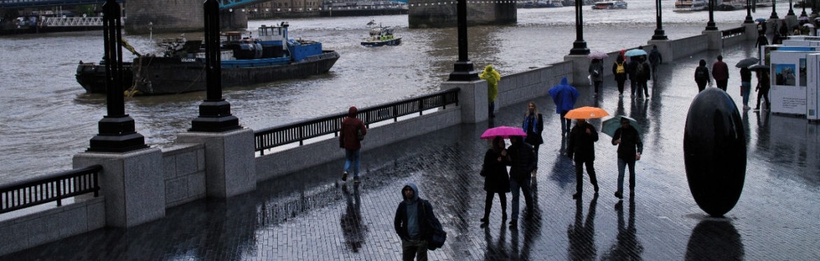 Tower Bridge area in the rain with silhouetted people with colourful umbrellas street photography