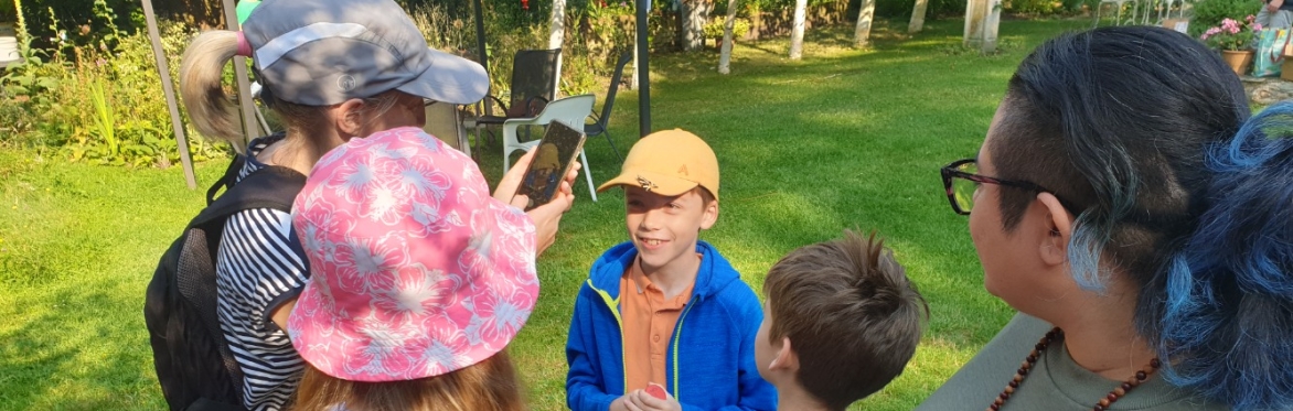 Boy with moth on his cap and 4 other people looking at it