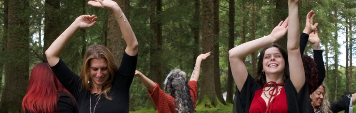 Women dancing in the woods, dressed somewhat witchily!