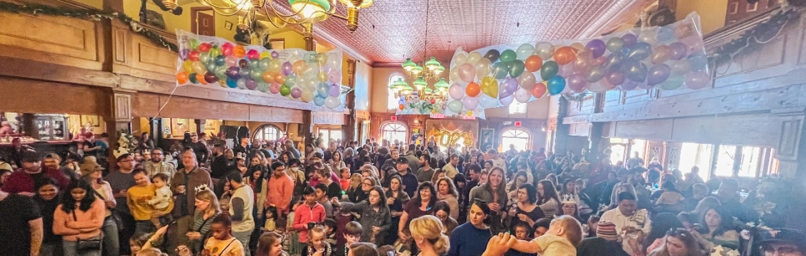 A group of people gather under balloons, preparing for a balloon drop
