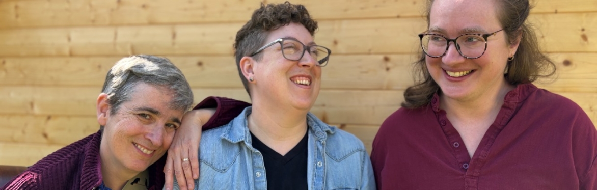 Patti Powell, Erinn Doncaster, and Ali Romanow standing in front of a wood wall, laughing